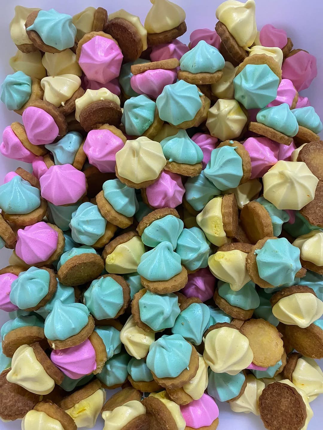 Bolachinhas cobertas de suspiro cor-de-rosa, azul e amarelo
